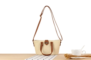 Detail of straw woven handbag featuring brown leather straps and golden twist lock closure