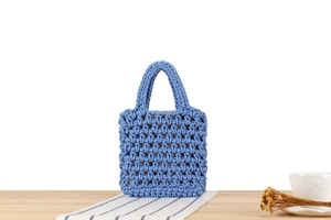 Detailed close-up of blue hand-woven hollow handbag with textured rope pattern and inner lining