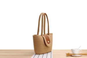 Detail of woven beach bag with brown leather flap and elegant pearl closure