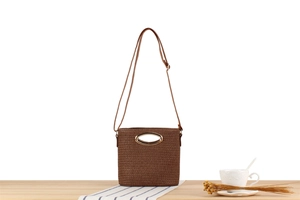 Detail of dark brown woven paper rope crossbody bag with golden oval metal handle