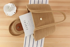 Top view of a khaki woven tote bag with magnetic clasp on a wooden desk with a coffee cup