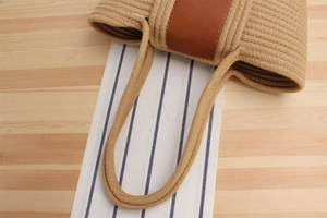 Detailed close-up of woven tote bag with brown leather trim and sturdy braided handle