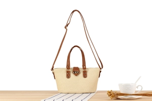 Detail of woven crossbody bag with brown leather strap and gold metal twist lock