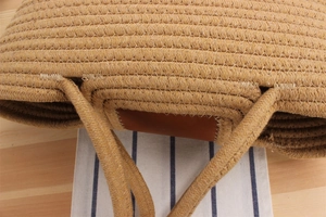Macro detail of hand-woven straw beach bag showing leather reinforced handles and stitching
