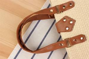 Close-up of straw woven tote with brown leather handles and gold metal rivet details