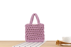 Detail of lavender handmade woven tote bag with hollow mesh texture on a wooden table