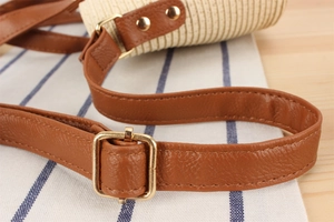 Detail of brown leather strap with gold buckle and texture on woven beach bag