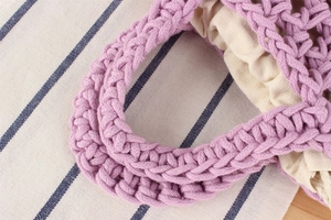 Detail shot of purple woven handbag with rope handle and cream cotton lining