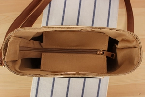 Top view of woven paper rope bag with zipper compartment and brown leather straps