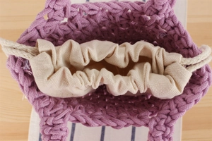 Close-up of purple hand-woven bag featuring beige canvas drawstring inner liner