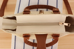 Detailed top view of a woven straw tote with leather handles and gold zipper closure