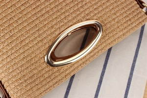 Close-up of woven straw texture with a round golden metal handle on a crossbody bag