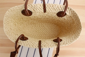 Top view of beige straw tote bag with spacious interior and brown leather handles