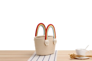 Detail of handmade cotton rope woven bucket bag with rainbow handle and white tassels