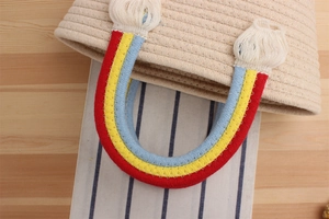 Detail of handmade cotton rope bag with colorful rainbow handle and white tassel accent