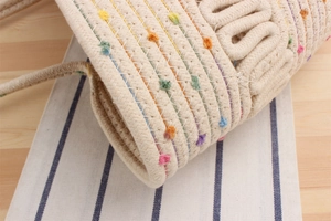 Vue détaillée du sac de plage en coton tressé avec des accents touffetés colorés