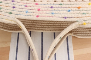 Détail du sac à bandoulière en coton avec coutures arc-en-ciel et petits pompons