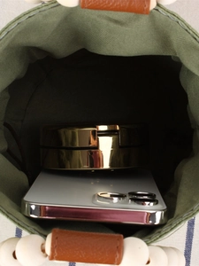 Green woven bucket bag interior showing capacity with smartphone and accessories