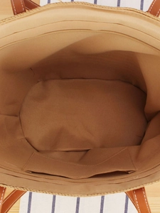 Spacious woven tote bag interior with zipper closure and smooth brown leather handles