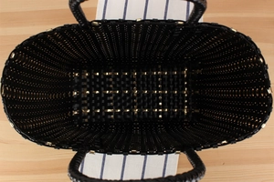 Vue de dessus d'un sac tressé noir avec des clous dorés et un intérieur spacieux
