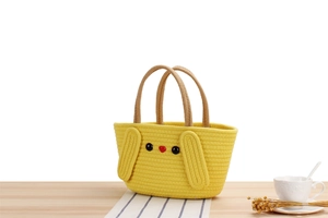 Close-up of cute cartoon woven cotton handbag with bunny ears on a textured table