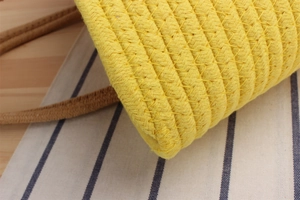 Close-up of yellow cotton rope woven basket featuring thick texture and brown leather handles