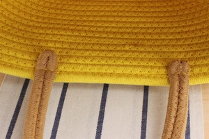 Detail of yellow cotton woven bag with brown handle showing stitch and texture quality