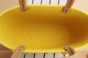 Close-up of yellow cotton woven storage basket with durable brown rope handles