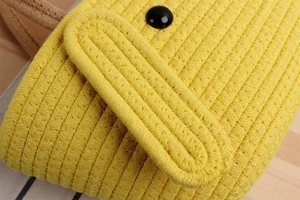 Close-up of bright yellow cotton cord woven bag featuring a contrast black button fastener