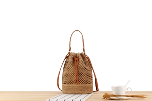 Detail of woven straw bucket bag showing brown leather drawstring and textured mesh weave