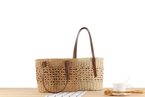 Detail of straw woven tote bags with leather straps on a minimalist wooden table