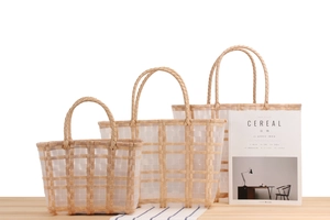 Three-piece set of woven lattice tote bags with wood-textured handles on a wooden table