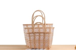 Three-piece nesting set of transparent plaid woven baskets with handles on wood table