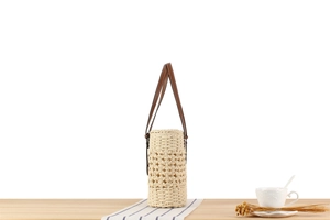 Detailed close-up of a hollow woven straw bucket bag on a minimalist wooden table