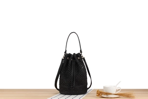 Detail of black woven bucket bag with drawstring closure on a wooden surface