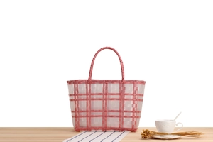 Detail of handwoven pink and white checkered plastic basket with durable round handles