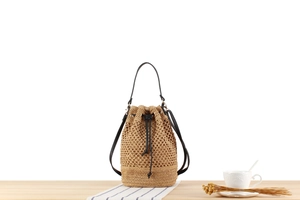 Close-up of handwoven straw bucket bag featuring black drawstring and textured hollow weave