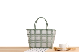 Detail of green and white checkered woven tote bag handles on a wooden table