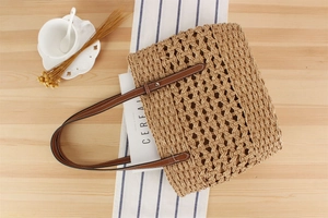 Flat lay of large paper rope woven tote bag with leather handles on a wooden table