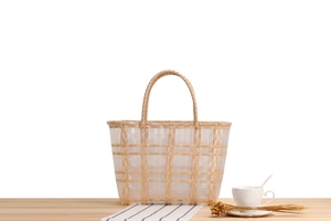 Detail of woven lattice tote bag with white and yellow stripes on a wooden desk