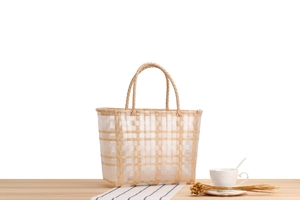 Detail of woven beach tote with beige straw handles and transparent grid patterns