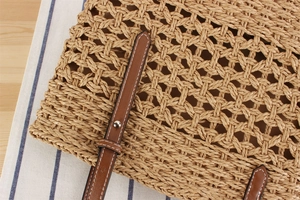 Detail of paper rope woven bag featuring brown leather strap with white contrast stitching