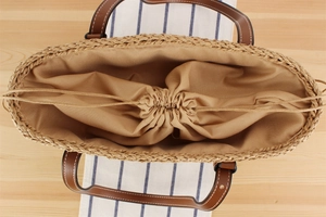 Detail of paper rope woven tote with brown leather handles and drawstring lining