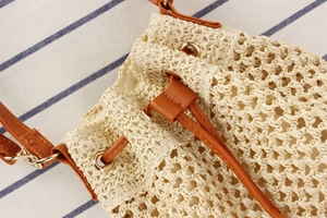Detail of woven straw bucket bag showing cream texture and brown drawstring closure