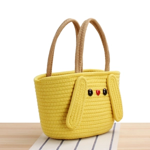 Cute yellow cotton woven handbag with rabbit ears and brown handles on wood surface