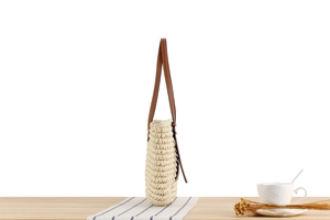 Close-up of beige woven tote bag with brown leather strap detail and spacious interior