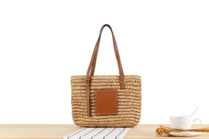 Detail shot of the hand-woven straw tote bag with brown leather patch and shoulder straps