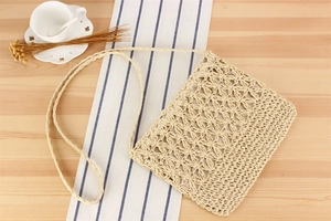 Detail of handwoven paper rope crossbody bag with floral cutouts and beige texture