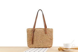Close-up of woven straw tote bag with brown leather handles and natural texture