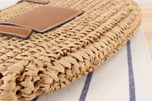 Close-up of woven straw texture with brown leather detail and white contrast stitching